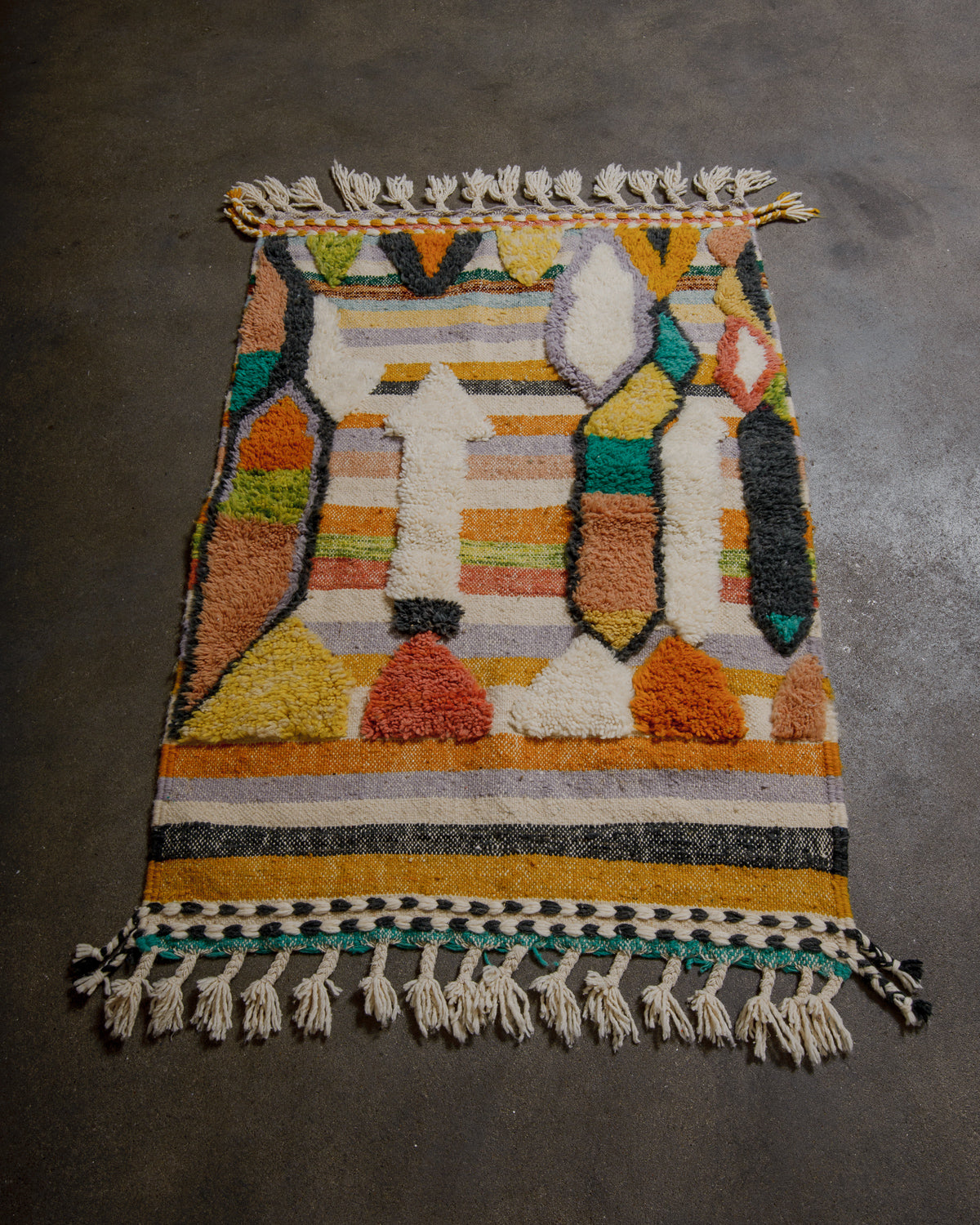 Colorful woven rug with geometric pattern on a dark surface